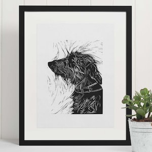 May include: Black and white linocut print of a dog looking up. The dog has a collar and is depicted in a stylized, minimalist style.