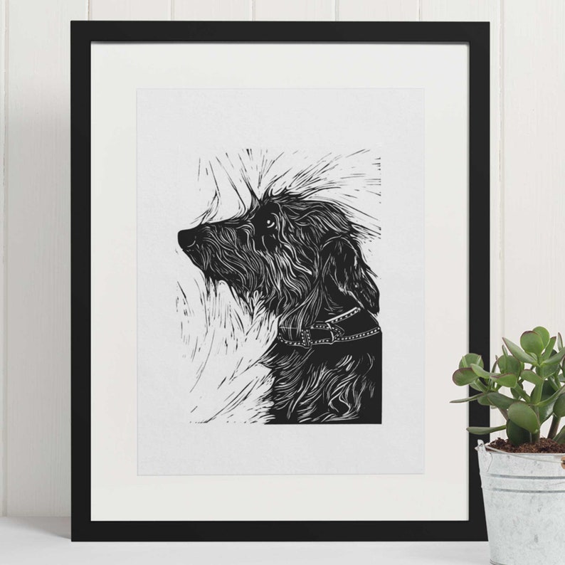 May include: Black and white linocut print of a dog looking up. The dog has a collar and is depicted in a stylized, minimalist style.