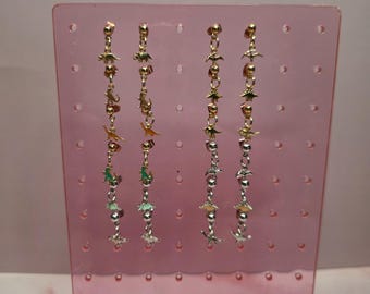 May include: Four long dangle earrings featuring a vertical chain of small metallic dinosaur charms and spherical beads. The two left earrings are gold-toned, while the two right earrings feature a mix of gold-toned and silver-toned dinosaur charms.