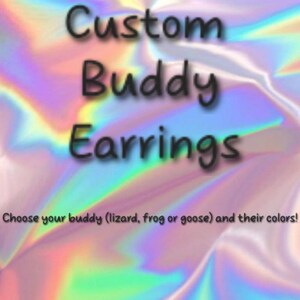 May include: A digital graphic with a holographic, iridescent background featuring the black text Custom Buddy Earrings. Below this, smaller black text reads: Choose your buddy (lizard, frog or goose) and their colours! The design is centred.