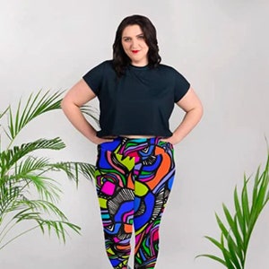 May include: A woman wearing a black short-sleeved shirt and colorful leggings with an abstract design. The leggings feature a variety of colors, including blue, green, pink, orange, and yellow.