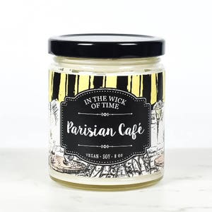 Puede incluir: Una vela en tarro de cristal con tapa negra. La etiqueta dice "In the Wick of Time Parisian Caf&eacute;" con un dise&ntilde;o en blanco y negro. La vela es vegana y de soja, y contiene 227 gramos.