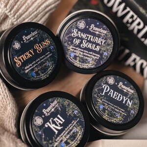 Puede incluir: Cuatro peque&ntilde;as latas de metal negro con etiquetas que presentan diferentes aromas y nombres: Sticky Buns, Sanctuary of Souls, Kai y Paedyn. Cada lata es una vela de soja de 4 oz.