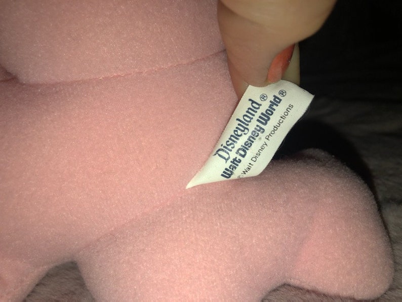 May include: Pink plush toy with a white tag that reads "Disneyland Walt Disney World Walt Disney Productions".