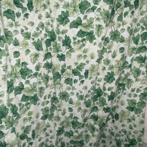 May include: Green and white fabric with a leafy pattern. The fabric has a subtle texture and a light, airy feel.