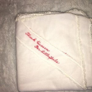 May include: White baby blanket with lace trim and red embroidered text that reads "Thank Heaven for Little Girls".