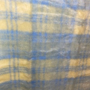 May include: A blue and cream plaid fabric with a fuzzy texture.