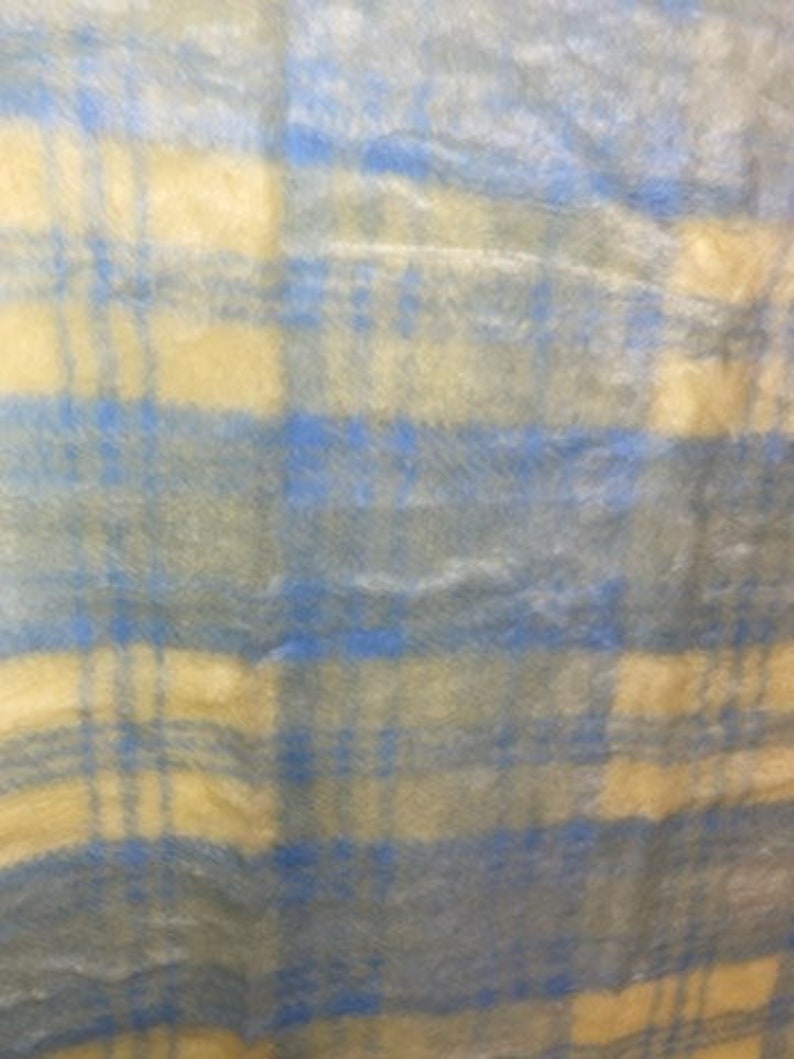 May include: A blue and cream plaid fabric with a fuzzy texture.