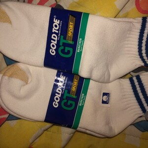 May include: Two pairs of white athletic socks with blue and white stripes. The socks are labeled "Gold Toe GT Sport Marathon Sport Socks".