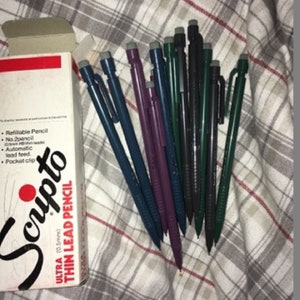 May include: A pack of Scripto Ultra Thin Lead Pencils in a variety of colors, including black, blue, green, and purple. The pencils are 0.5mm and have a pocket clip.