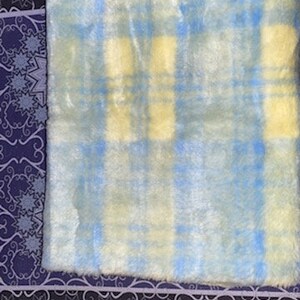 May include: A soft, fluffy rug with a blue and yellow plaid pattern. The rug is made of faux fur and has a light, airy feel.