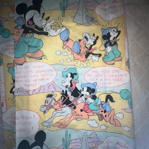 May include: A vintage yellow fabric with a cartoon image of Mickey Mouse and his friends in a desert setting. The text "Of all the tough luck!" appears in a speech bubble above Mickey Mouse. The fabric has a cartoonish style and features a repeating pattern of cacti and mountains.