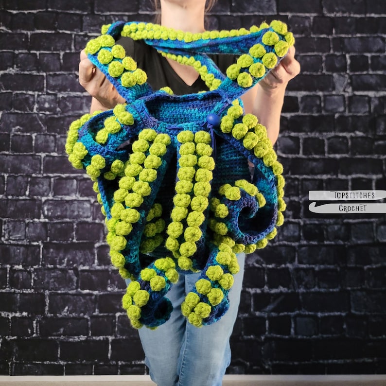 May include: A blue and green crocheted octopus-shaped bag with lime green bobbles. The bag has a button closure and shoulder straps. The text "TOPSTITCHES CROCHET" is in the lower right corner.