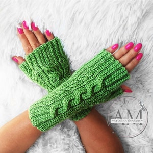 May include: Green crocheted fingerless gloves with a cable knit pattern. The gloves are shown on a person's hands with pink nail polish.