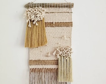 May include: A beige and brown woven wall hanging with fringe. The hanging features three white and beige tassels.