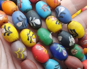 May include: A collection of colorful glass beads with intricate designs. The beads are oval shaped and have a variety of colors, including blue, red, green, yellow, and brown. The beads are strung together on a string.
