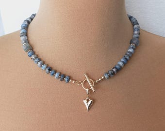 Op de afbeelding: Een ketting van blauwe edelstenen met een gouden hartbedel en een schuifsluiting.