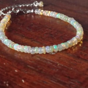 May include: A delicate bracelet made of iridescent opal beads, strung on a silver chain.
