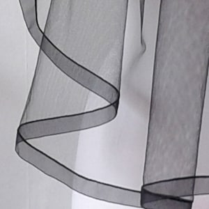 May include: Black tulle veil with a single layer and a wide, black satin ribbon trim.