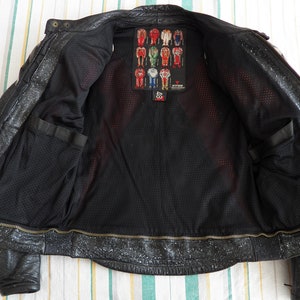 K&ouml;nnte beinhalten: Schwarze Leder-Motorradjacke mit Rei&szlig;verschluss und Mesh-Futter. Die Jacke hat ein Etikett mit dem Text "Alpinestars" und der Nummer "48".