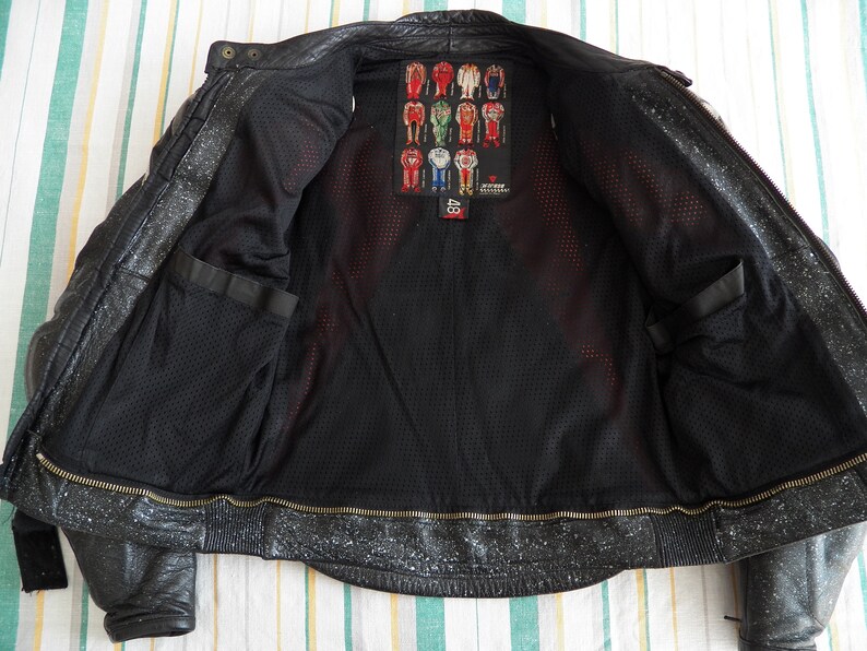 K&ouml;nnte beinhalten: Schwarze Leder-Motorradjacke mit Rei&szlig;verschluss und Mesh-Futter. Die Jacke hat ein Etikett mit dem Text "Alpinestars" und der Nummer "48".