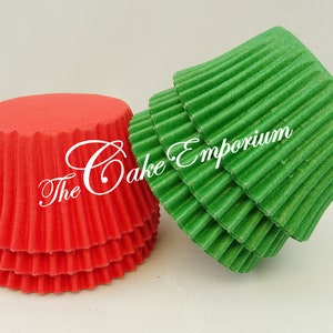May include: Red and green cupcake cases. The cases are fluted and have a shiny finish. The text "The Cake Emporium" is visible on the red cases.