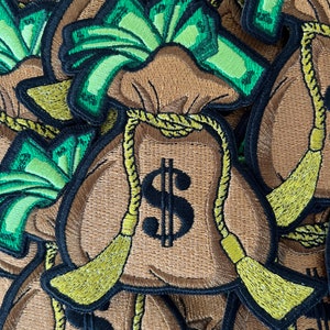 May include: A pile of brown money bags with green dollar bills peeking out of the top. Each bag has a black dollar sign embroidered on the front and a yellow rope tied around the top.