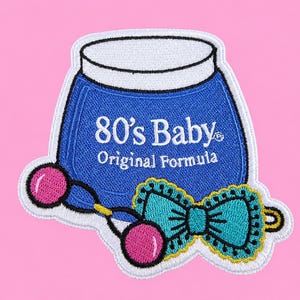 May include: An embroidered patch featuring a blue jar with a white lid, labeled 80's Baby Original Formula in white text. In front of the jar is a pair of pink ball hair ties connected by a blue cord and a teal bow with a yellow scalloped border.