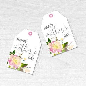Puede incluir: Dos etiquetas de regalo blancas con dise&ntilde;os florales rosas y amarillos. El texto en las etiquetas dice "Feliz D&iacute;a de la Madre".