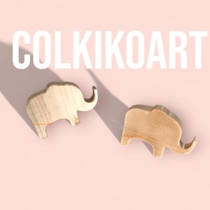 May include: Two wooden elephant figurines on a pink background. The elephants are light brown and have a simple, stylized design. The text "COLKIKOART" is displayed in large white letters above the elephants, with "Only on Etsy" below.
