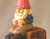 Pequeño gnomo sentado sobre un bloque de juguete, mano tallada en madera por Russell Scott, gnome escandinavo