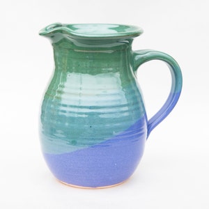 May include: A blue and green ceramic pitcher with a wide mouth and a handle. The pitcher is glazed with a smooth finish.