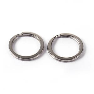 K&ouml;nnte beinhalten: Zwei silberne Schl&uuml;sselringe, jeder mit einer glatten, kreisf&ouml;rmigen Form. Die Ringe sind aus Metall und haben eine polierte Oberfl&auml;che.