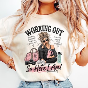 May include: A cream-colored t-shirt featuring a graphic of a person with a messy bun, sunglasses, and a leopard print headband. The text reads: WORKING OUT Because punching people is frowned upon and wine doesn't burn calories! So Here I Am!