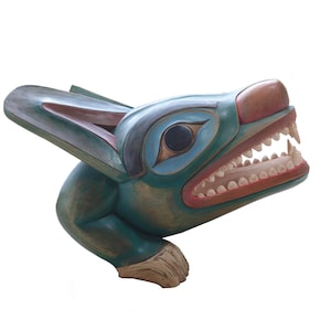 Peut inclure: Sculpture en bois sculpté d'une tête d'animal stylisée, peut-être un loup ou un ours, dans des tons de bleu sarcelle, bleu et marron. La sculpture présente des dents acérées, un œil détaillé et un design amérindien traditionnel.
