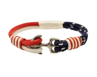 Op de afbeelding: Een nautische armband van rood, wit en blauw touw met een ankergesp.