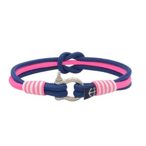 May include: A nautical-themed bracelet featuring a blue and pink rope design. The bracelet has a stainless steel clasp and pink and white striped accents. A small navy blue tag with a white anchor is attached.