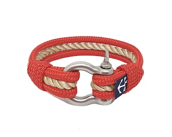 Puede incluir: Pulsera de cuerda roja y beige con cierre de ancla de plata. La pulsera tiene una etiqueta azul marino con un ancla blanca.