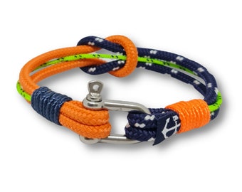 May include: A bright orange and navy blue rope bracelet with a silver clasp. The rope is woven with a green stripe and has a small anchor charm.