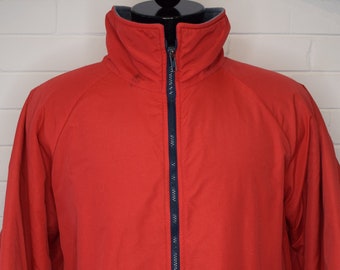 May include: A red zip-up jacket with a navy blue lining and cuffs. The jacket has a stand-up collar and a zip closure.