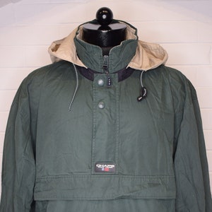 Könnte beinhalten: Eine grüne Kapuzenjacke mit Reißverschluss und Druckknopfverschluss. Die Jacke hat einen Logo-Patch mit der Aufschrift "Chaps Ralph Lauren" und einer kleinen amerikanischen Flagge.