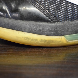 Peut inclure: Gros plan sur la semelle d'une chaussure noire et blanche avec une semelle jaune. La semelle a une bande verte autour du bord.