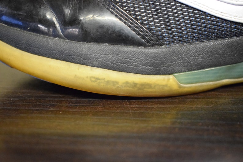 Peut inclure: Gros plan sur la semelle d'une chaussure noire et blanche avec une semelle jaune. La semelle a une bande verte autour du bord.