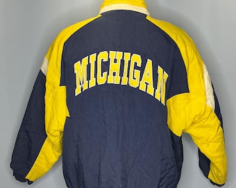 May include: A blue and yellow vintage puffer jacket with the word "MICHIGAN" in yellow lettering on the back.