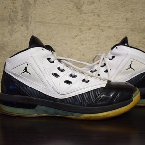 Peut inclure: Une paire de chaussures de basket-ball blanches et noires avec un panneau en mesh noir et bleu sur le c&ocirc;t&eacute;. Les chaussures ont une semelle ext&eacute;rieure en caoutchouc noir et une semelle interm&eacute;diaire blanche.