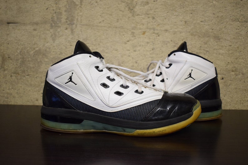 Peut inclure: Une paire de chaussures de basket-ball blanches et noires avec un panneau en mesh noir et bleu sur le c&ocirc;t&eacute;. Les chaussures ont une semelle ext&eacute;rieure en caoutchouc noir et une semelle interm&eacute;diaire blanche.