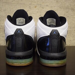 Peut inclure: Une paire de chaussures de basket-ball noires et blanches avec un accent bleu. Les chaussures ont une empeigne en cuir verni noir et une languette en cuir blanc. Les chaussures ont une semelle ext&eacute;rieure en caoutchouc noir avec une semelle interm&eacute;diaire bleu translucide.