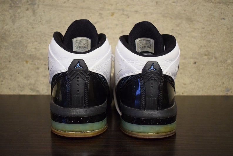 Peut inclure: Une paire de chaussures de basket-ball noires et blanches avec un accent bleu. Les chaussures ont une empeigne en cuir verni noir et une languette en cuir blanc. Les chaussures ont une semelle ext&eacute;rieure en caoutchouc noir avec une semelle interm&eacute;diaire bleu translucide.