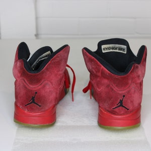 May include: A pair of red suede Air Jordan trainers with black accents and a black "Air Jordan" label on the tongue.