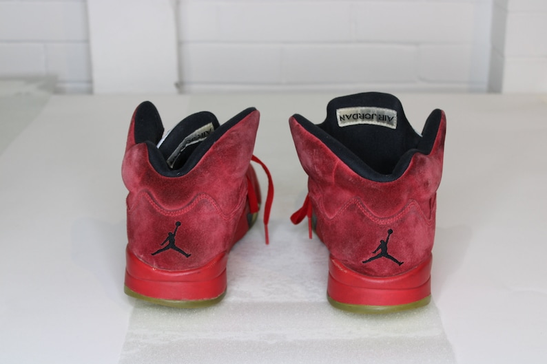 May include: A pair of red suede Air Jordan trainers with black accents and a black "Air Jordan" label on the tongue.
